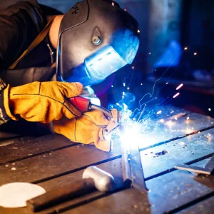 Worker cutting metal with plasma equipment on plant.