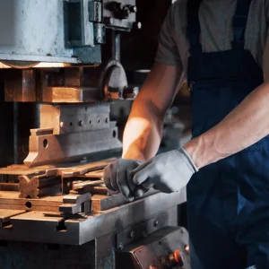 Portrait of a young worker in a hard hat at a large metalworking plant. The engineer serves the machines and manufactures parts for gas equipment.