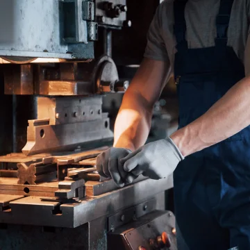 Portrait of a young worker in a hard hat at a large metalworking plant. The engineer serves the machines and manufactures parts for gas equipment.