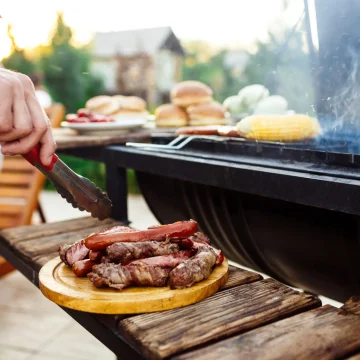 Young handsome men roasting barbecue on grill in cottage countryside. Copy space.